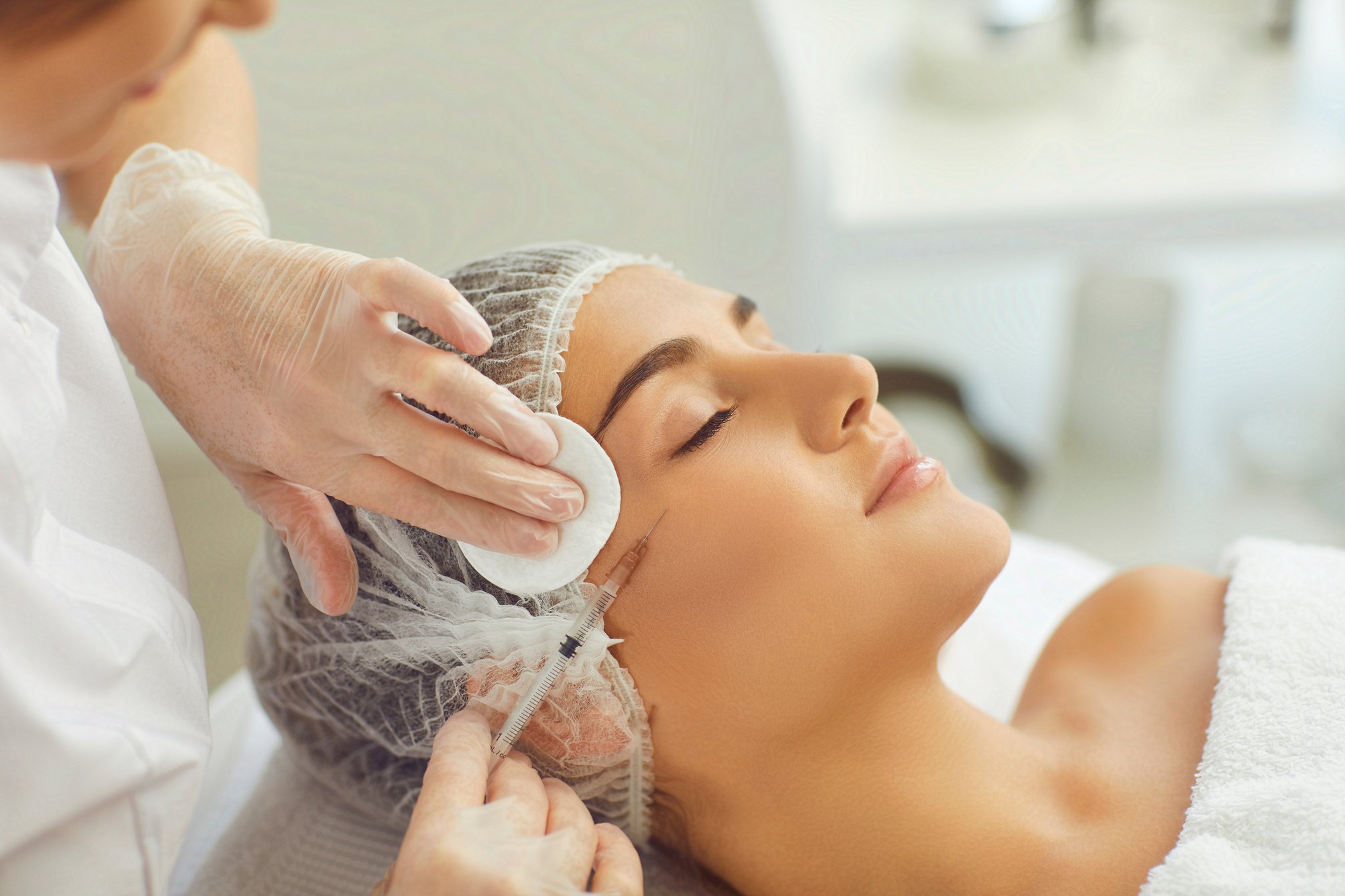 Cosmetologist Wiping Skin with Cotton Pads during Facial Beauty Botox Injection for Young Womans Cheek